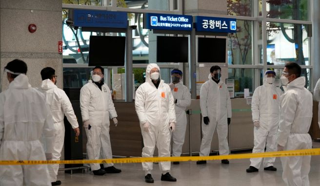 Quarantäne-Beauftragte in Schutzkleidung warten in der Ankunftshalle des internationalen Flughafens Incheon auf Reisende, um sie zu ihren Quarantäne-Unterkünften zu führen. 